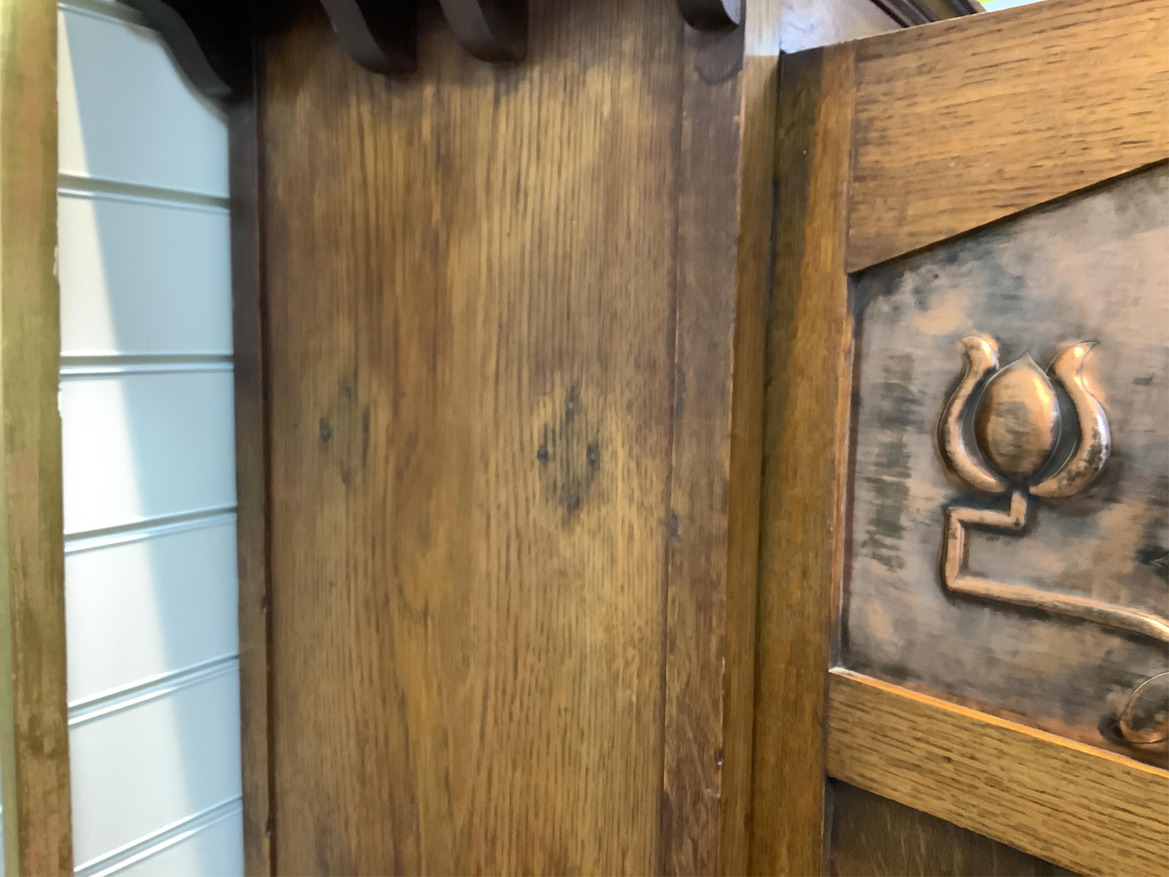 Manner of Liberty & Co: An Arts and Crafts embossed copper mounted oak hall cupboard